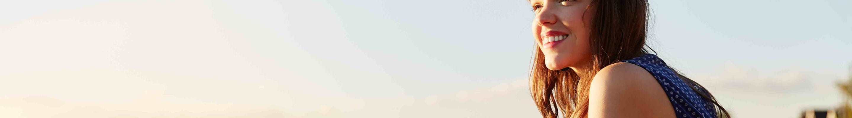 Vrouw zit aan het water en is gelukkig omdat ze in goede gezondheid is.