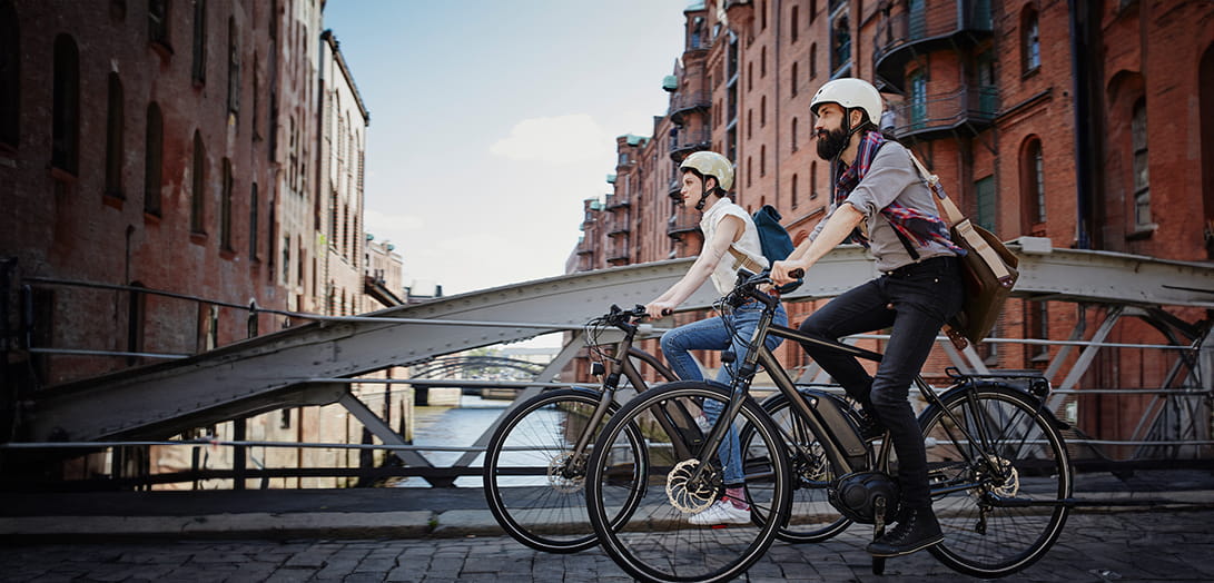 Man en vrouw fietsen op een brug: een schadegeval kunnen ze aangeven via hun fietsverzekering.