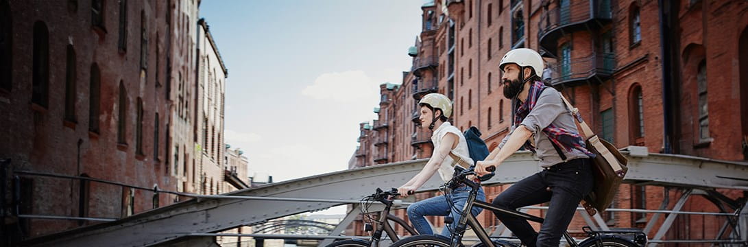 Un couple fait du vélo sur un pont: en cas de dommage, ils peuvent le déclarer grâce à leur assurance Vélo.