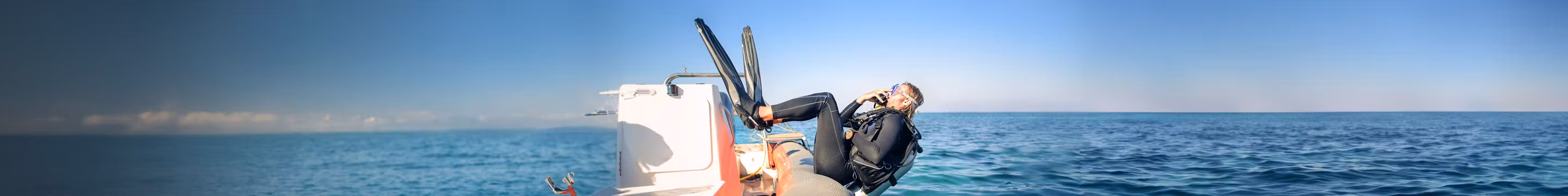 Man duikt in het water op reis: een schadegeval kan hij aangeven via zijn reisverzekering.