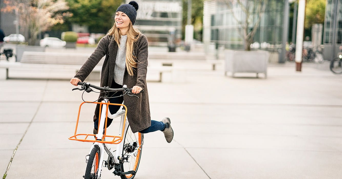 Jonge vrouw op een fiets, beschermd bij schade aan anderen dankzij haar Familiale verzekering.